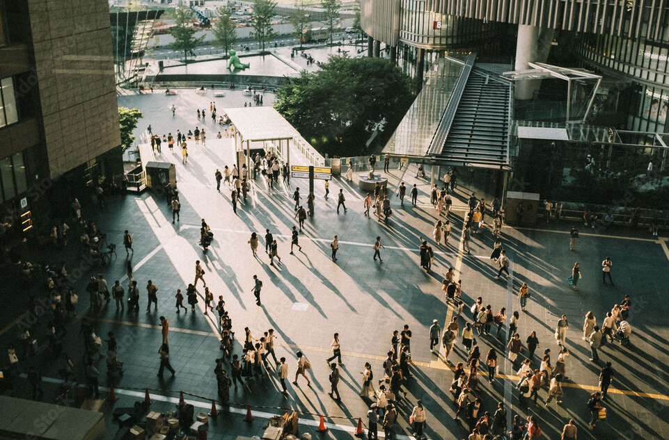 Directly above view of pavement with people walking towards buildings